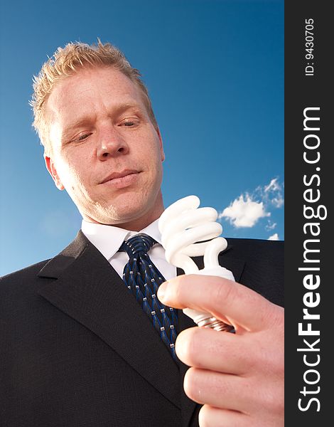 A businessman shows he is environmentally aware by holding a lightbulb. A businessman shows he is environmentally aware by holding a lightbulb