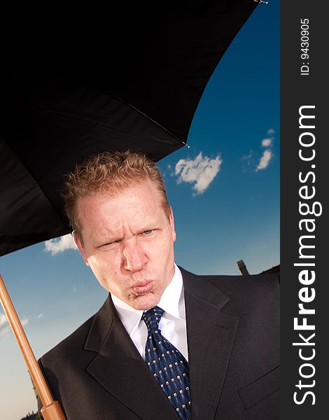 A sad businessman holds up umbrella on a sunny day. A sad businessman holds up umbrella on a sunny day