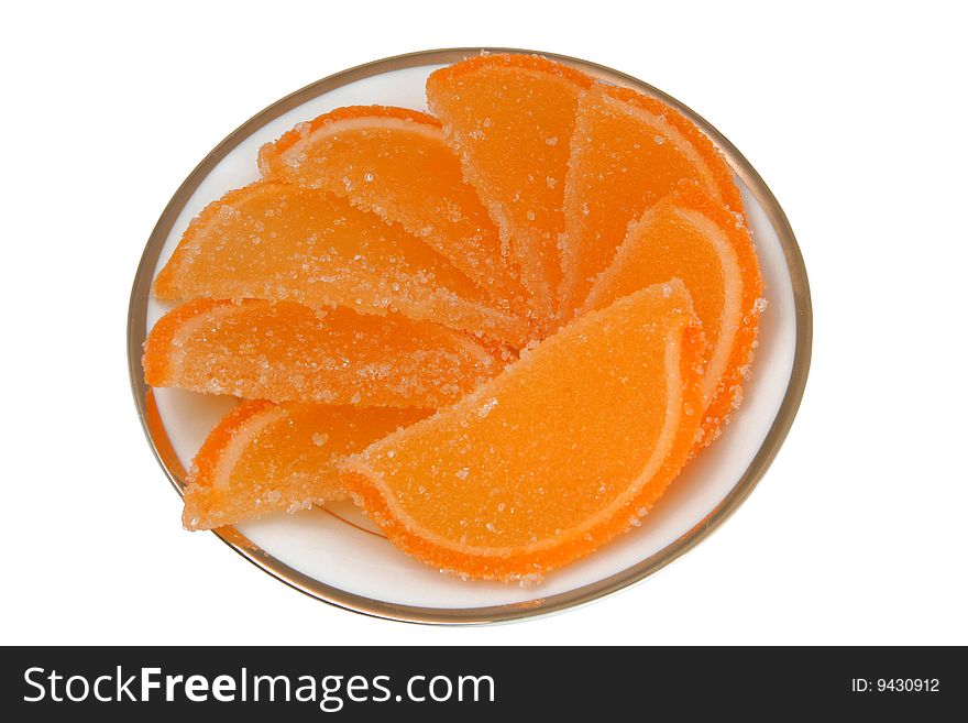 Plate with fruit candy in the form of lemon segments on a white background