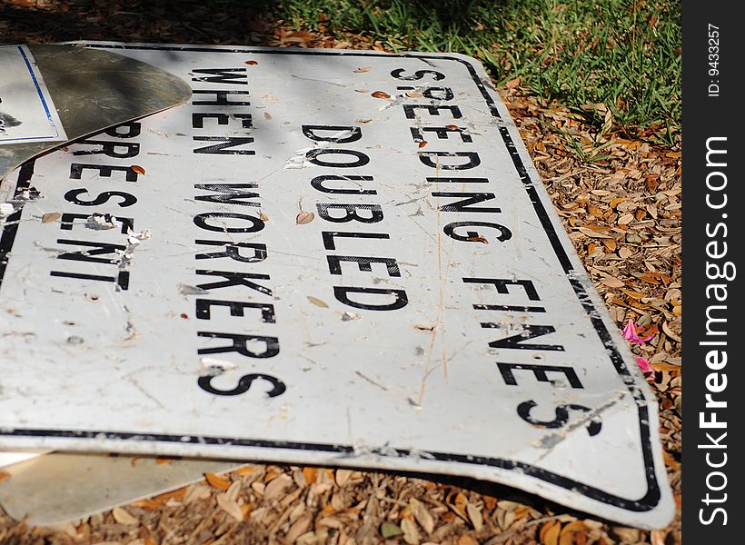 A crashed speeding fines doubled sign laying on the ground. A crashed speeding fines doubled sign laying on the ground.