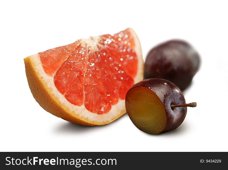 Grapefruit and plums on a white background