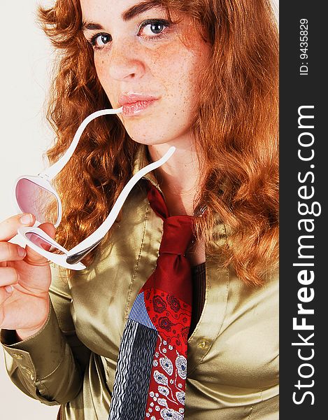 Pretty bright red haired woman in a gold blouse and necktie with an 
white sunglasses in close-up. Pretty bright red haired woman in a gold blouse and necktie with an 
white sunglasses in close-up.