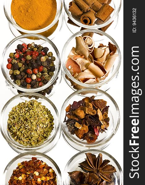 Eight different spices on a mirror with white background