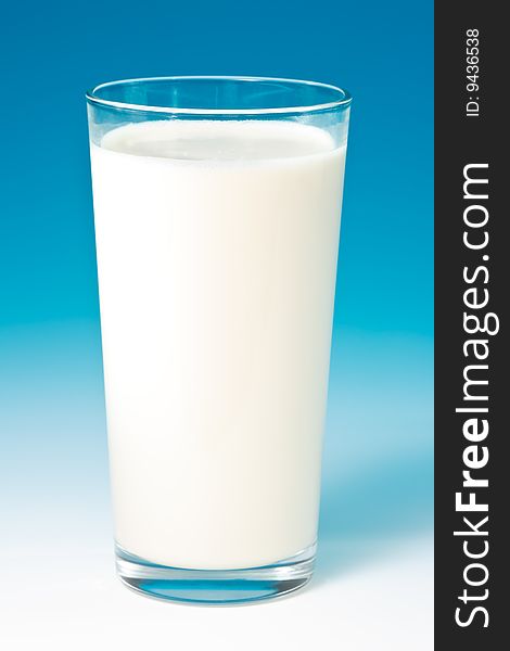 Cool fresh milk in a tall glass on blue gradient studio background.