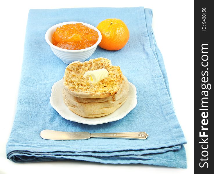 Buttered english muffin and marmalade on blue cloth background. Buttered english muffin and marmalade on blue cloth background.