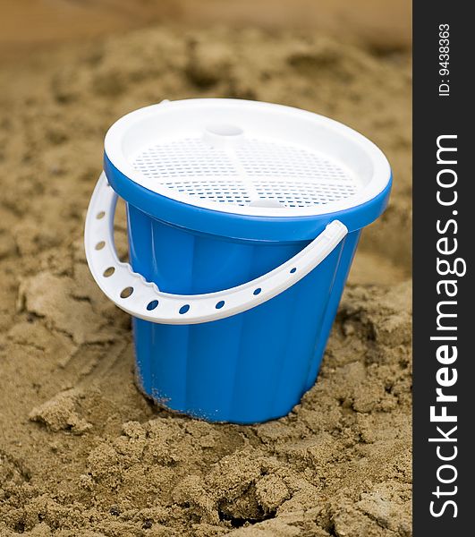 Children's dark blue plastic bucket in a sandbox. Children's dark blue plastic bucket in a sandbox