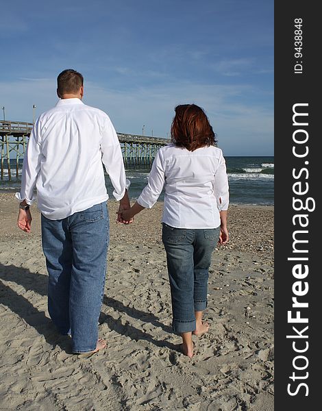 A young couple walking on the beach barefoot