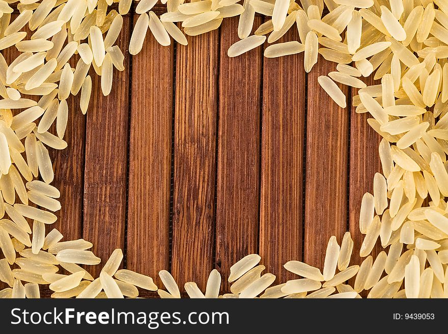 Frame of uncooked rice on bamboo mat with copy space.