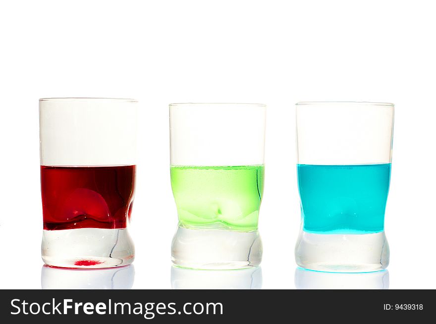 Three red green blue drinks in glasses on a white background