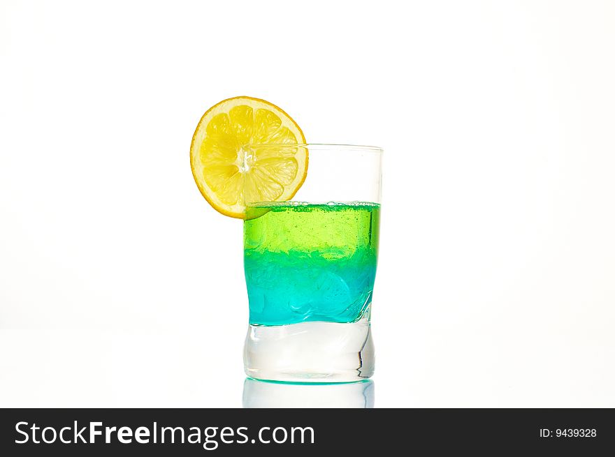 A colorful dring in a glass on a white background, with a lemon on the top. A colorful dring in a glass on a white background, with a lemon on the top