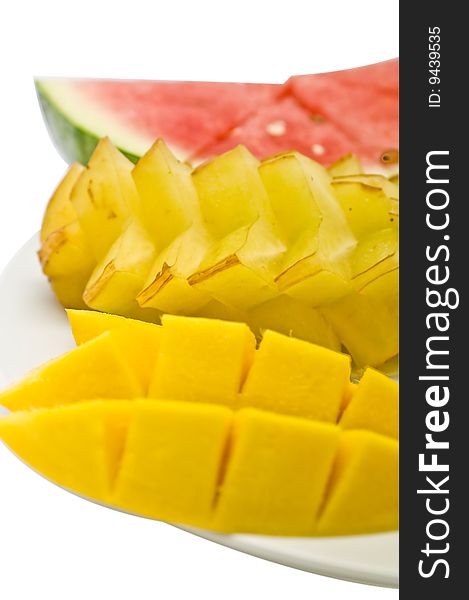Three types of tropical fruits sliced and arranged on a white plate: mango, starfruit and watermelon. Three types of tropical fruits sliced and arranged on a white plate: mango, starfruit and watermelon.