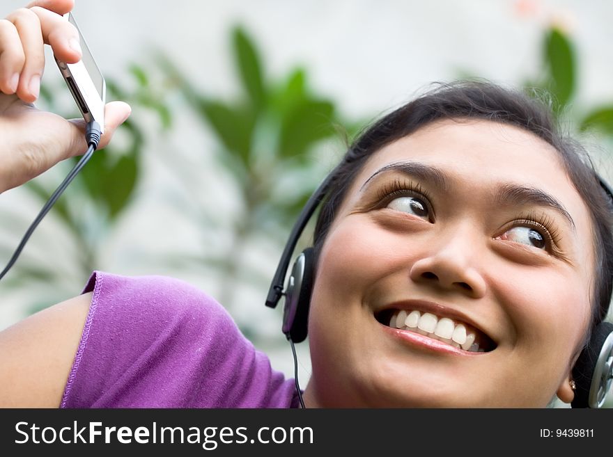 Beautiful asian young woman with headphone listening music from mp3 player. Beautiful asian young woman with headphone listening music from mp3 player