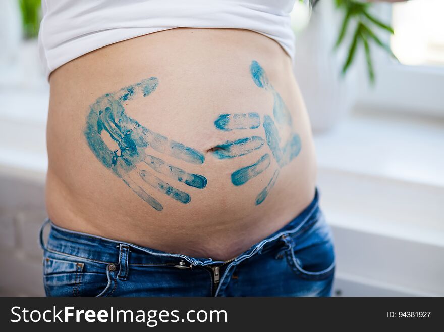 Close-up of a belly of a pregnant woman with prints of her palms