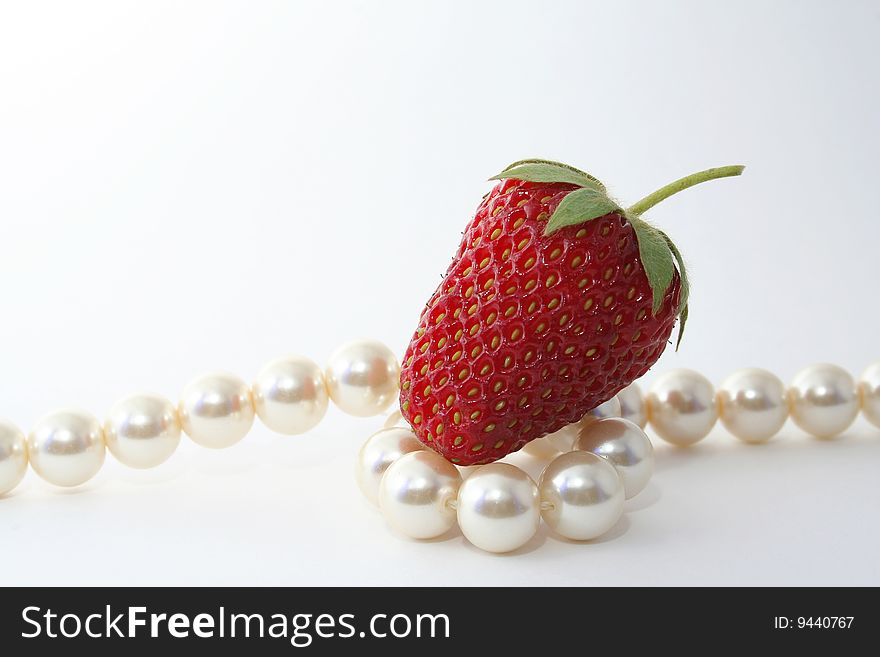 The Berries of the ripe strawberries and pearl necklace on white background. The Berries of the ripe strawberries and pearl necklace on white background.