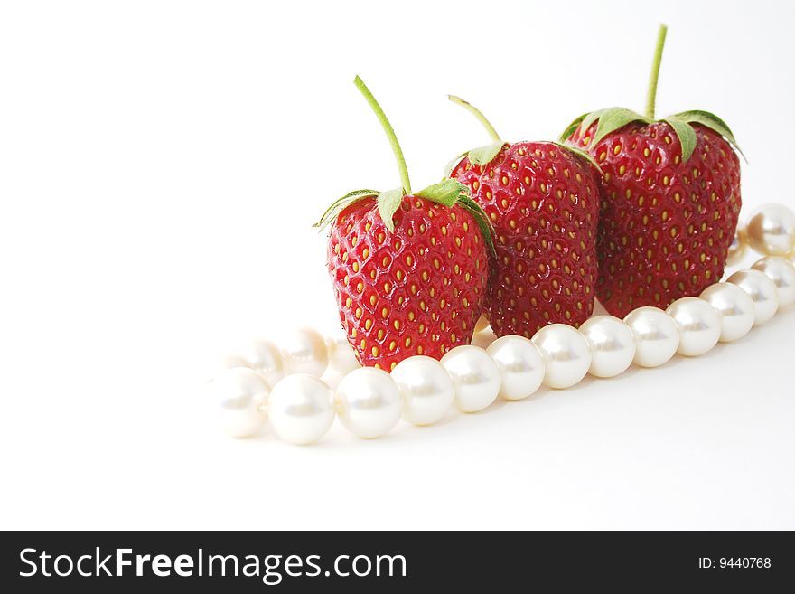 The Berries of the ripe strawberries and pearl necklace on white background. The Berries of the ripe strawberries and pearl necklace on white background.