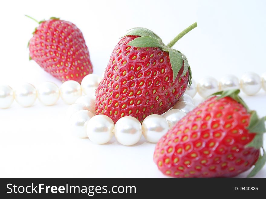 The Berries of the ripe strawberries and pearl necklace on white background. The Berries of the ripe strawberries and pearl necklace on white background.