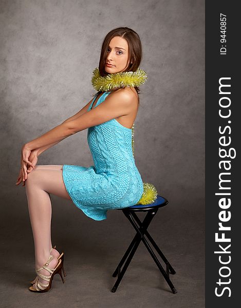 Young model in a blue dress on a grey background