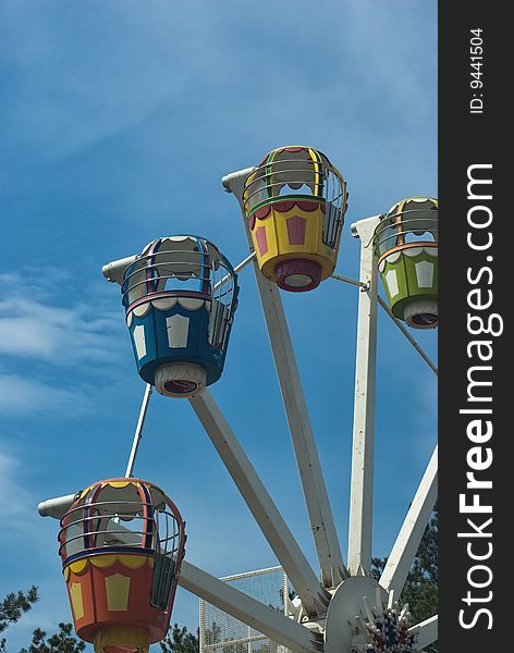 Popular attraction in park - a Ferris wheel on a background of the cloudy blue sky