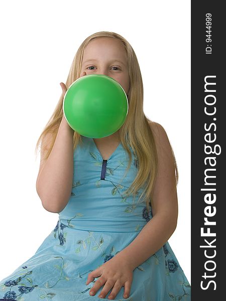 Girl in a blue dress blowing up a green balloon. Girl in a blue dress blowing up a green balloon