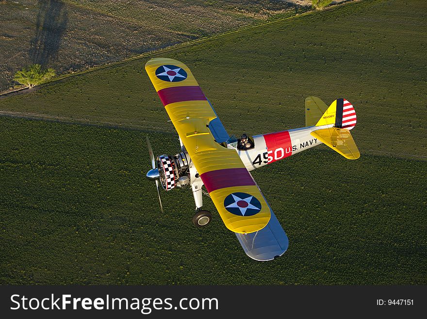 Yellow 1942 steerman flying over field. Yellow 1942 steerman flying over field