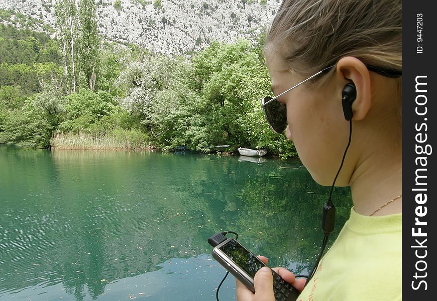 Girl listening music on cellular in the river. Girl listening music on cellular in the river