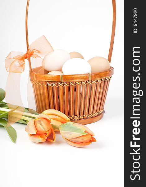 Eggs in a basket and orange tulips. Eggs in a basket and orange tulips