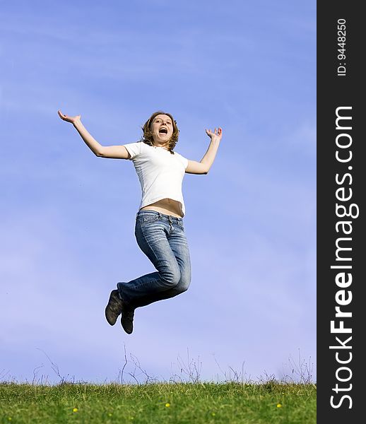 Young casual woman jumping on a summer field against blue sky. Young casual woman jumping on a summer field against blue sky