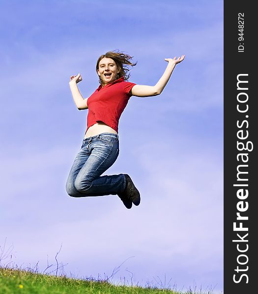 Young casual woman jumping on a summer field against blue sky. Young casual woman jumping on a summer field against blue sky