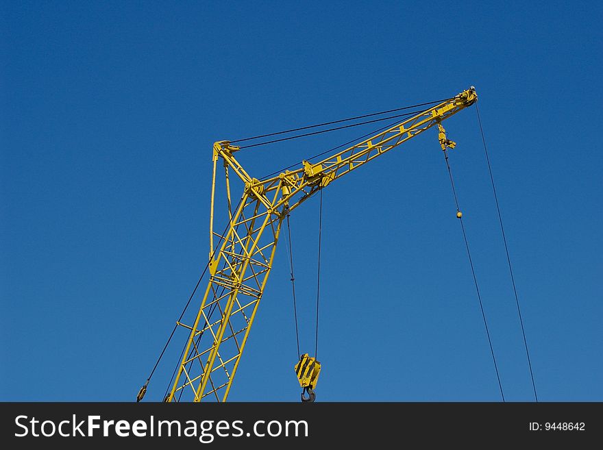 Yellow industrial crane on blue sky background. Yellow industrial crane on blue sky background