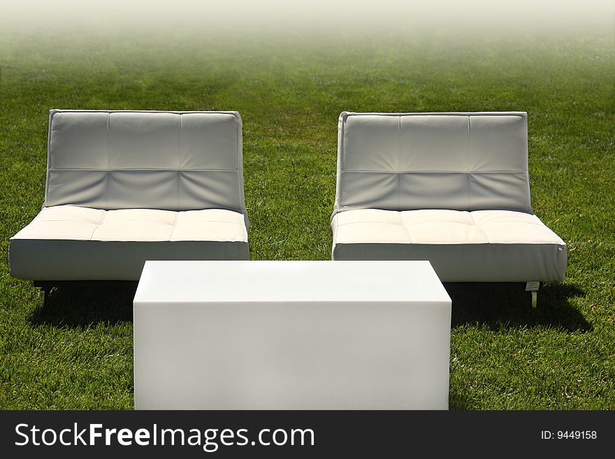 Modern white chairs and table in lawn with faded white background