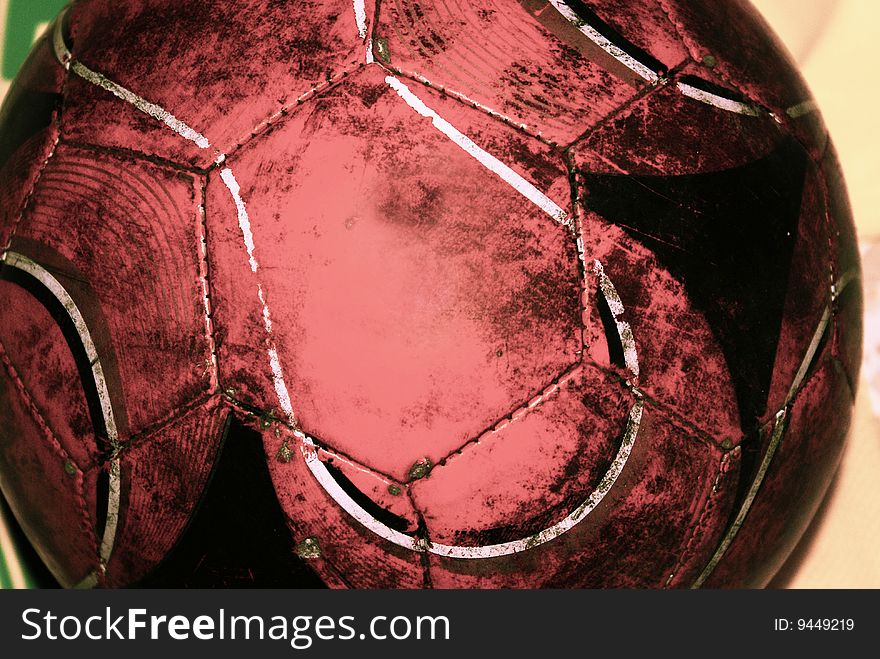 A rather used and torn football. Its color is red along with black with a deep yellow background. A rather used and torn football. Its color is red along with black with a deep yellow background