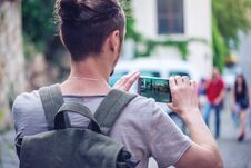 Man Backpack Makes A Photo On Your Smartphone On A City Street Royalty Free Stock Photography