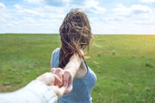 Follow Me, Attractive Brunette Girl Holding The Hand Of The Leads In A Clean Green Field, Steppe With Clouds Royalty Free Stock Photography