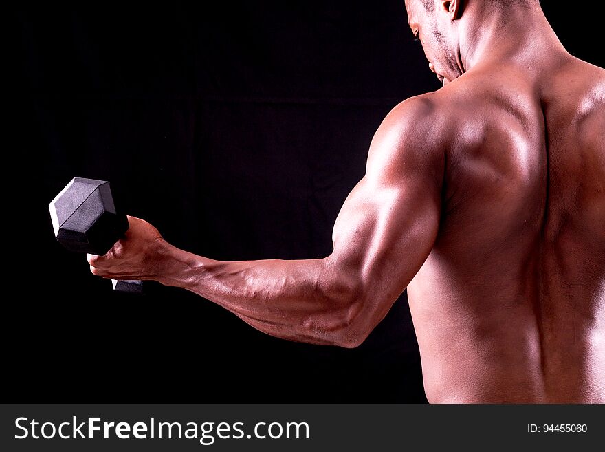 Man big muscles doing exercises with dumbbells over black background