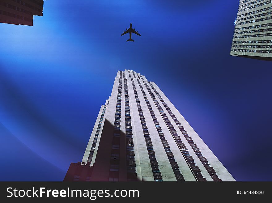 A plane flying over a skyscraper.