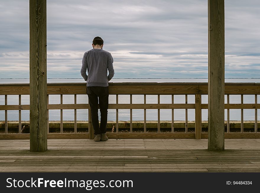 Man on railing overlooking ocean