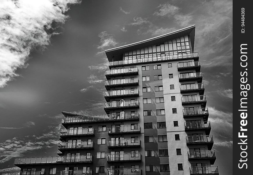 Facade of high rise apartment building against cloudy skies in black and white. Facade of high rise apartment building against cloudy skies in black and white.