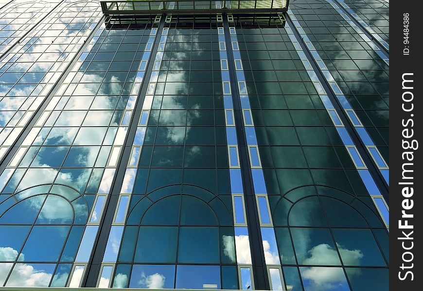 Blue skies and clouds reflecting in front of glass and steel modern building. Blue skies and clouds reflecting in front of glass and steel modern building.