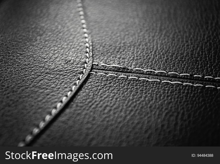 A black and white close up of a leather surface with seams.