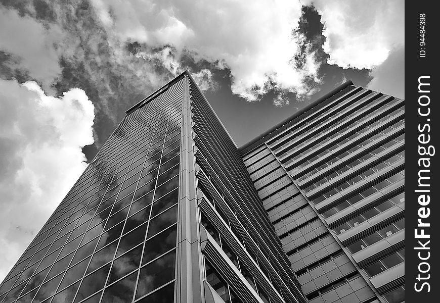 A monochrome photo of a modern high rise building from a low angle.
