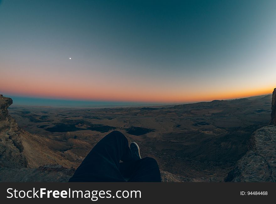 Orange glow of dawn on the horizon of a dark rocky landscape with some blue light in the sky and one star or planet prominent. Orange glow of dawn on the horizon of a dark rocky landscape with some blue light in the sky and one star or planet prominent.