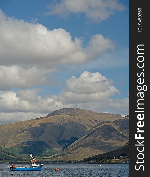 Blue boat on Loch Duich  with mountains behind and blue sky with interesting clouds. Blue boat on Loch Duich  with mountains behind and blue sky with interesting clouds.