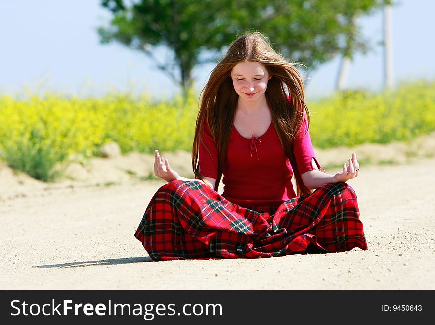 Meditating girl with long hair on country road