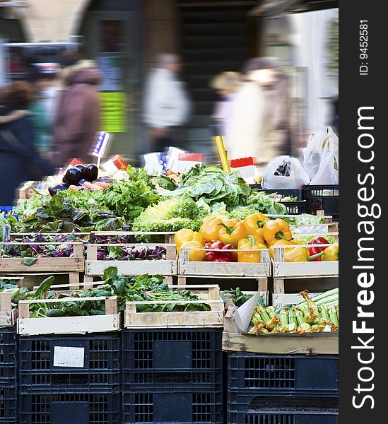 The colors of the vegetables on a typical bank of fruit and vegetables and the busy people walking on the background. The colors of the vegetables on a typical bank of fruit and vegetables and the busy people walking on the background