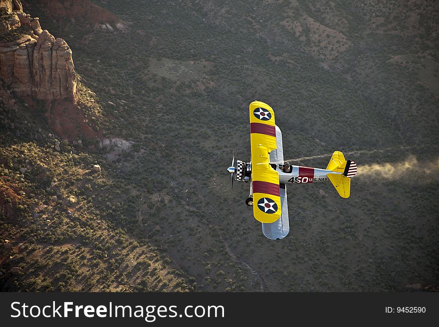 Yellow Biplane Over Desert