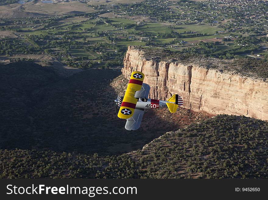 Yellow 1942 steerman flying over large rock canyon. Yellow 1942 steerman flying over large rock canyon.