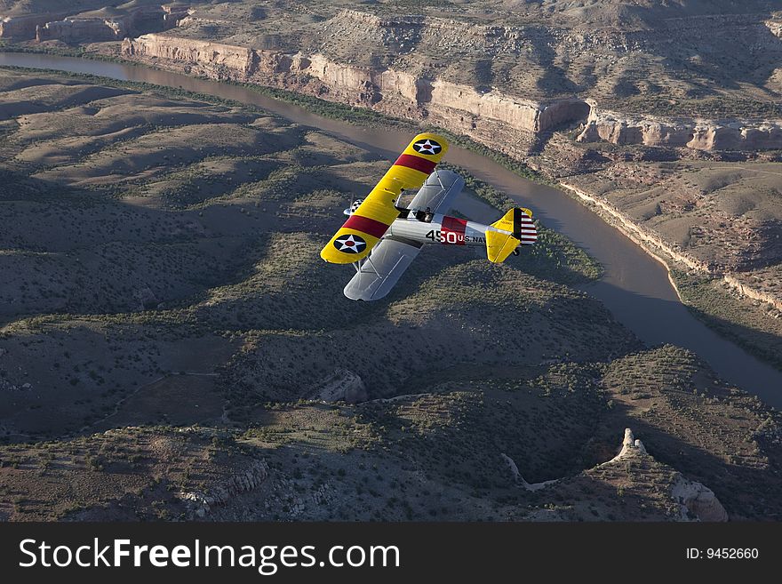 Yellow 1942 steerman flying over colorado river. Yellow 1942 steerman flying over colorado river