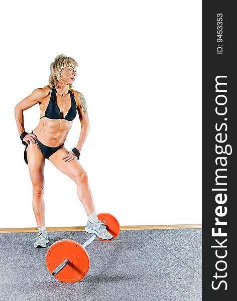 Young woman bodybuilder stands and leans against the weight. Young woman bodybuilder stands and leans against the weight