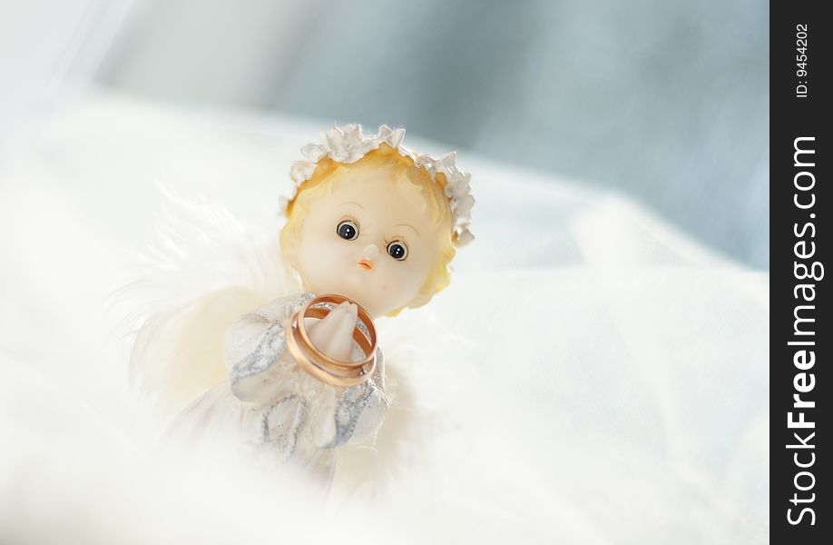 Photo of a figure of a little angel with gold wedding rings