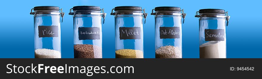 Buckwheat, Rice, Millet, Oat-Flakes, Semolina. Five containers with different groats. Over blue background